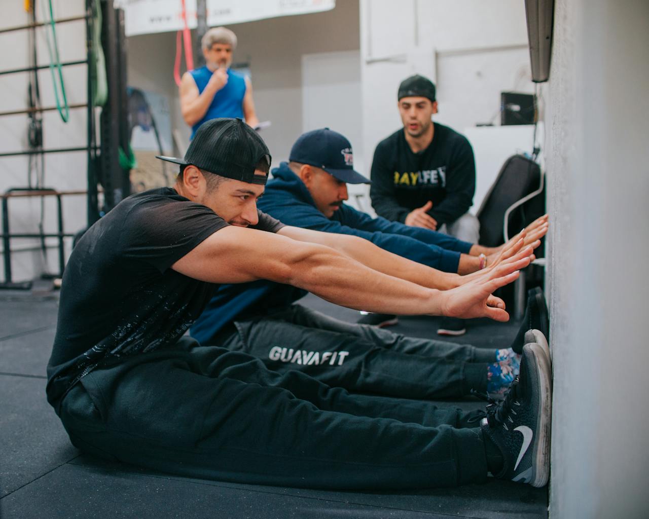 Men stretch during a workout session at an indoor gym, emphasizing fitness and teamwork.