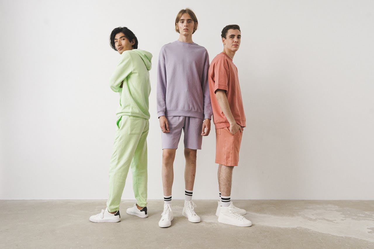 Three men in pastel casual outfits posing in a studio setting.